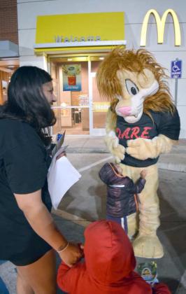 THIS YOUNGSTER HAPPILY GREETS the D.A.R.E Lion at the Sheriff’s Department Toys for Tots event at the Littlefield Mcdonald’s on Monday, Dec. 12th. (Photo by Ann Reagan)